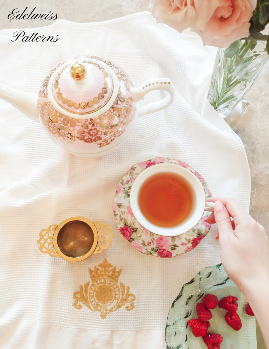 hand holding teacup with teapot and flowers